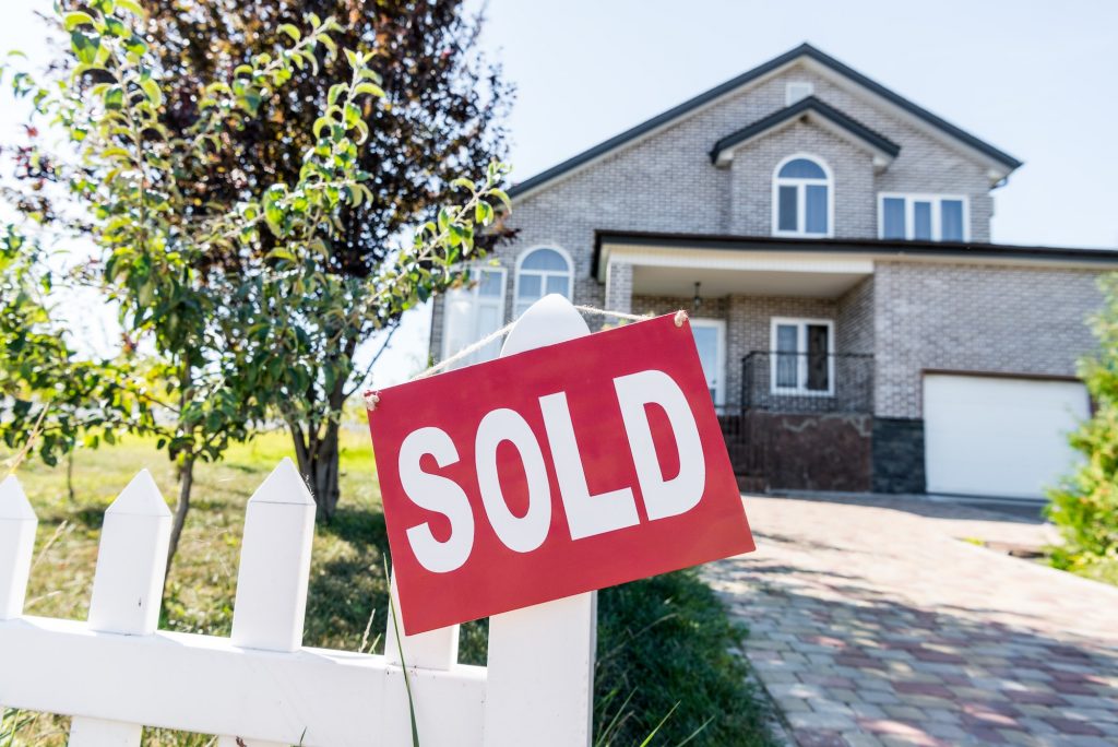 beautiful new house with sign sold hanging on fence